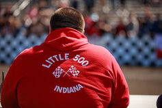 A male student in a Little 500 sweatshirt sits on the track sidelines at Bill Armstrong Stadium.